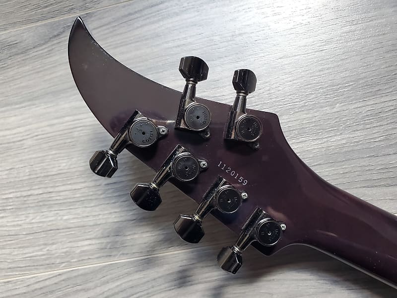 Close-up of a crimson guitar headstock with black tuning pegs and a serial number