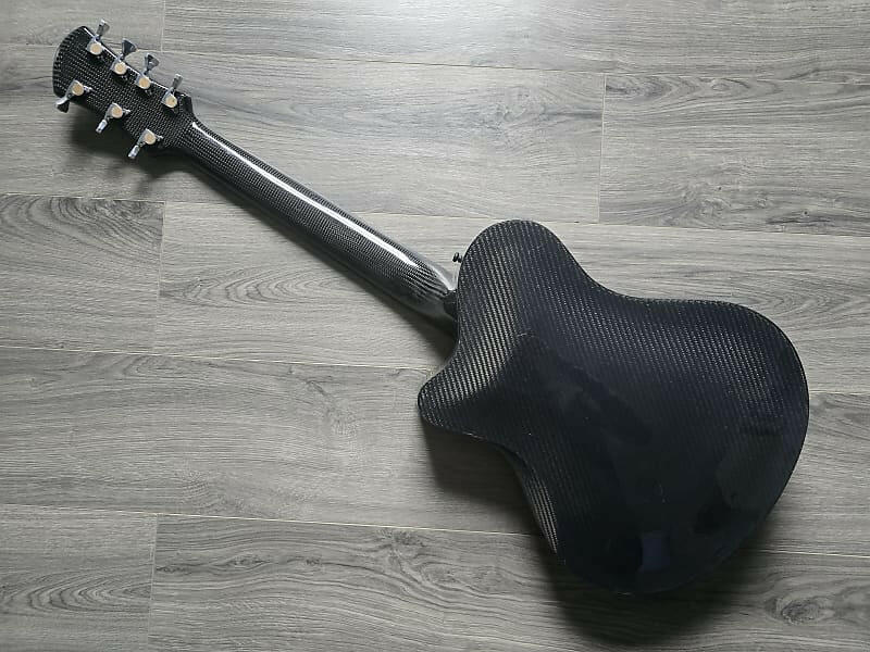 Gray carbon fiber acoustic guitar face down on a wooden floor