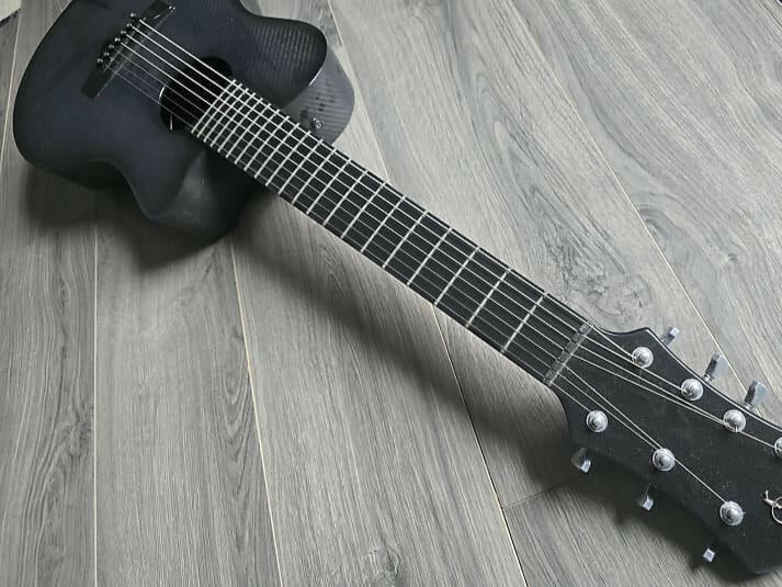 Dark gray acoustic guitar on a wooden surface
