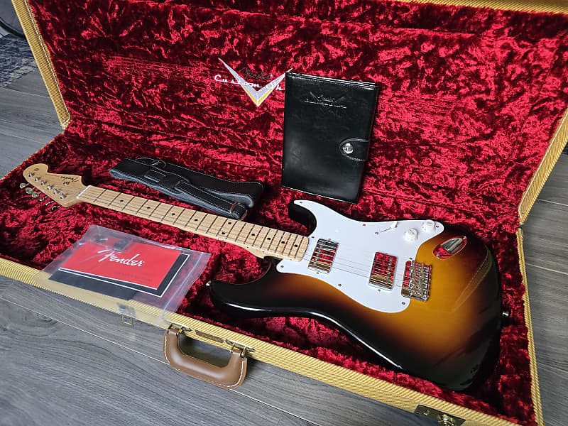 Fender electric guitar in a red-lined case with accessories.