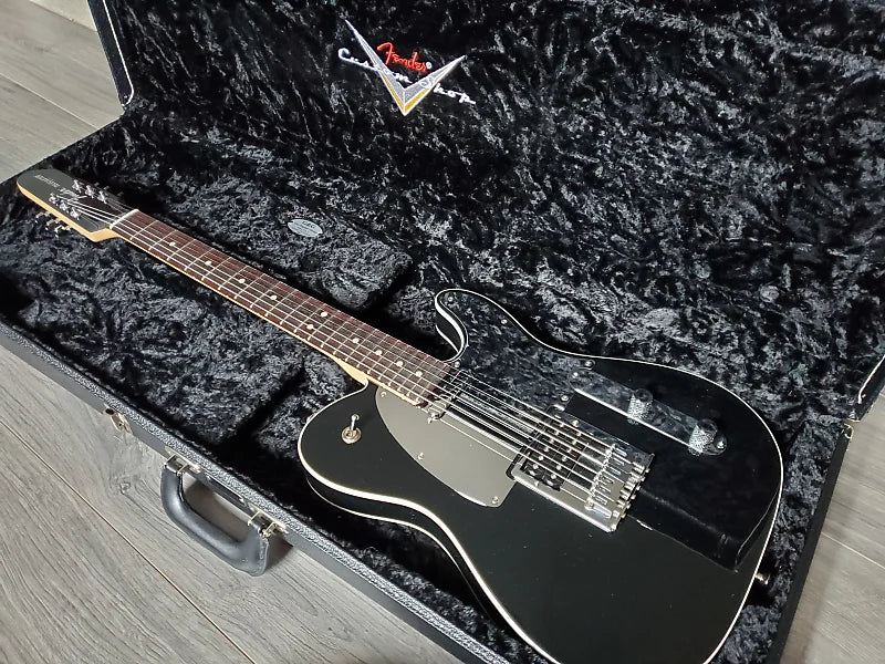 Black electric guitar in a Fender case on a wooden floor