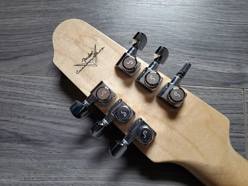 guitar headstock with metal tuning pegs and 'Fender' branding