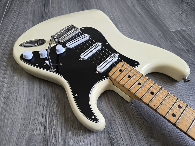 White and black electric guitar with wooden fretboard and stainless steel bridge and pickups