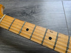 Close-up of a guitar neck with frets and strings on a wooden surface