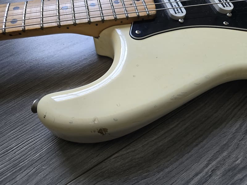 Close-up of a white electric guitar body on a wooden surface