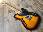 Angled artistic view of an electric guitar with a sunburst finish on a wooden floor