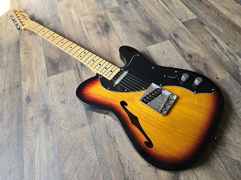 Angled artistic view of an electric guitar with a sunburst finish on a wooden floor