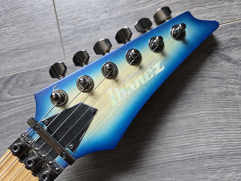 Guitar headstock with a blue and white gradient and the Ibanez logo
