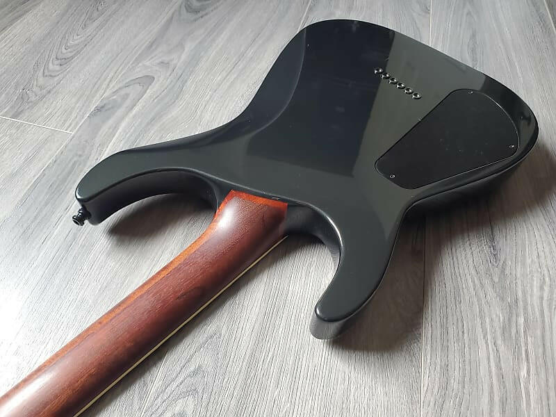 Guitar body with black pickguard and brown neck on a wooden surface