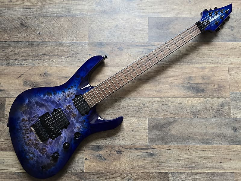 blue Jackson Pro Chris Broderick electric guitar with wooden surface background