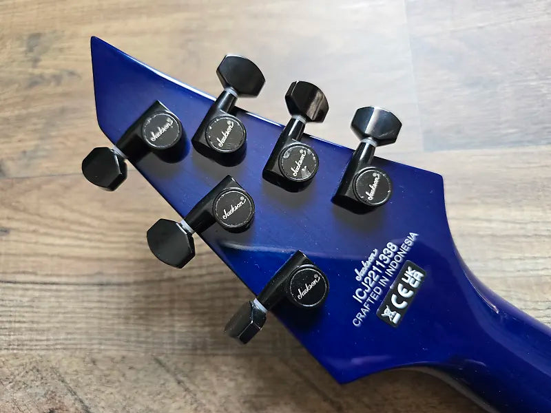 Blue guitar headstock with tuning pegs on a wooden surface