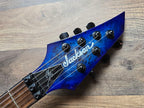 Blue electric guitar headstock with 'Jackson' branding on a wooden surface