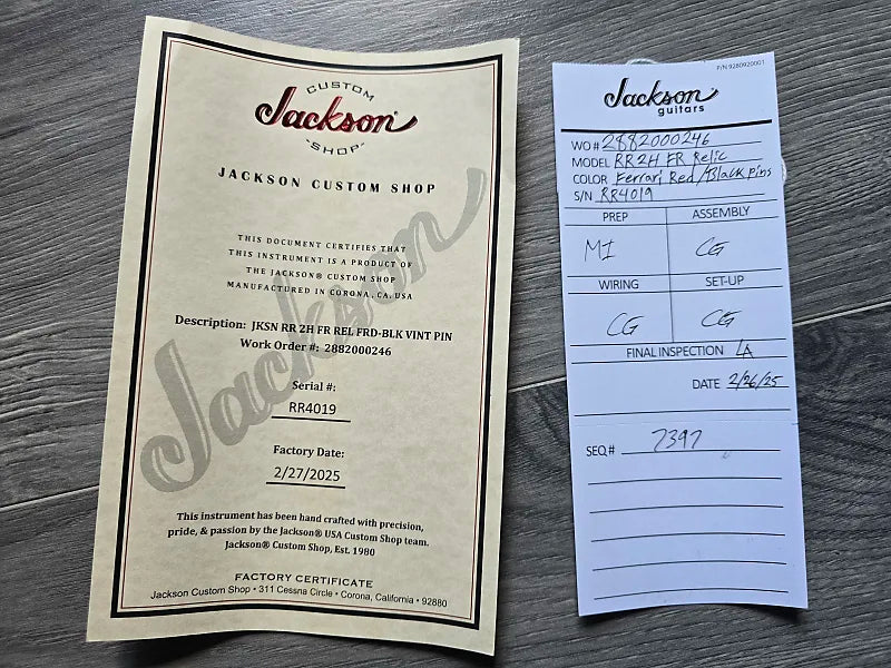 Jackson guitar factory certificate and inspection card on a wooden surface