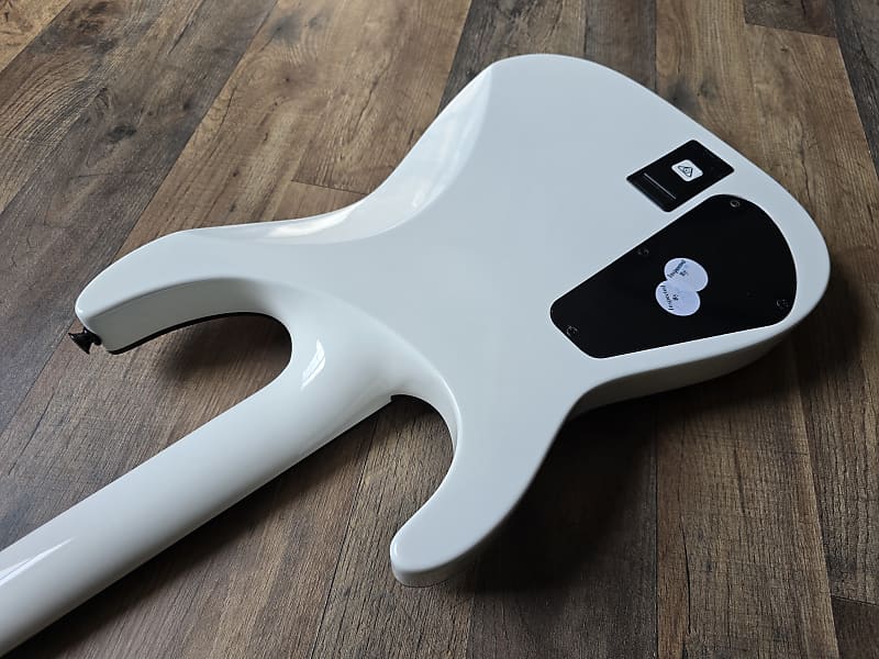 back of white electric guitar body lying on wooden surface