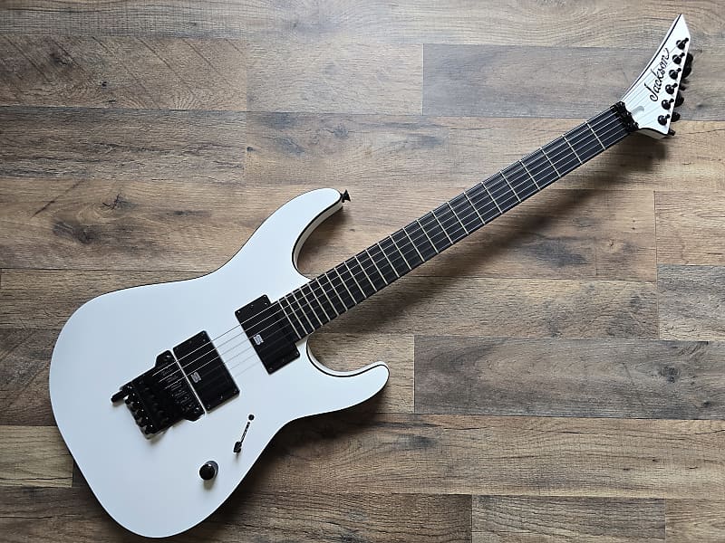 white Jackson Pro Mick Thomson with black hardware and ebony fretboard on a wooden background
