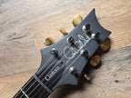 Guitar headstock with 'Paul Reed Smith Custom' branding on a wooden surface