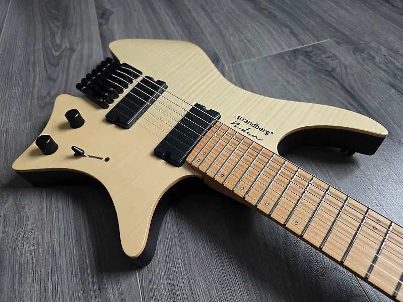 Electric guitar with a wooden body and black hardware on a gray wooden surface