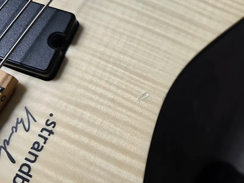Close-up of a guitar with 'Strandberg' branding on a textured surface.