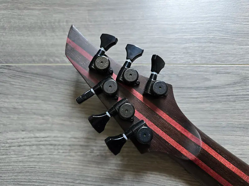 Close-up of a guitar headstock with tuning pegs on a wooden surface